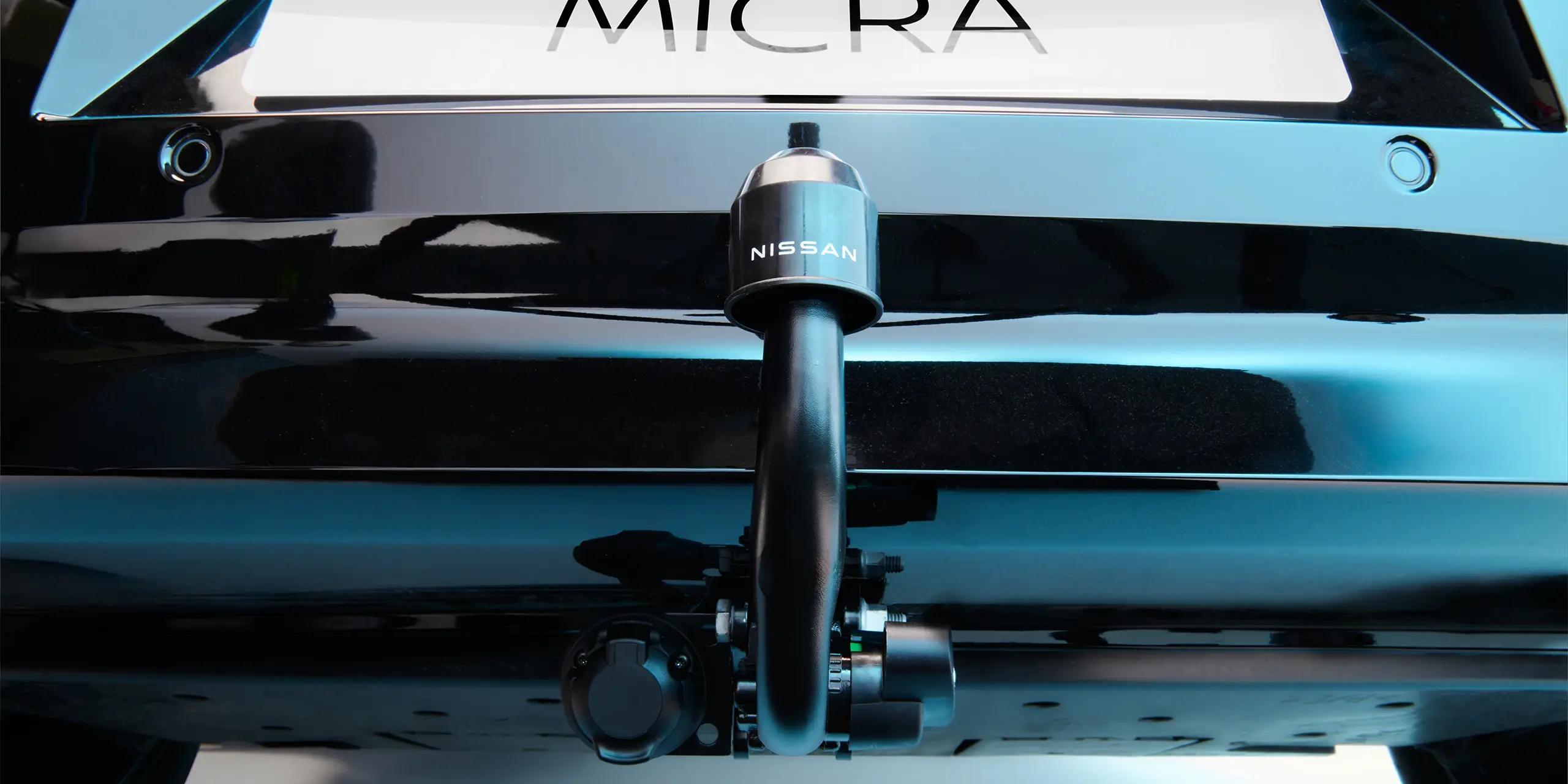 Close-up of a Nissan Micra's rear showing a trailer hitch with a Nissan logo.