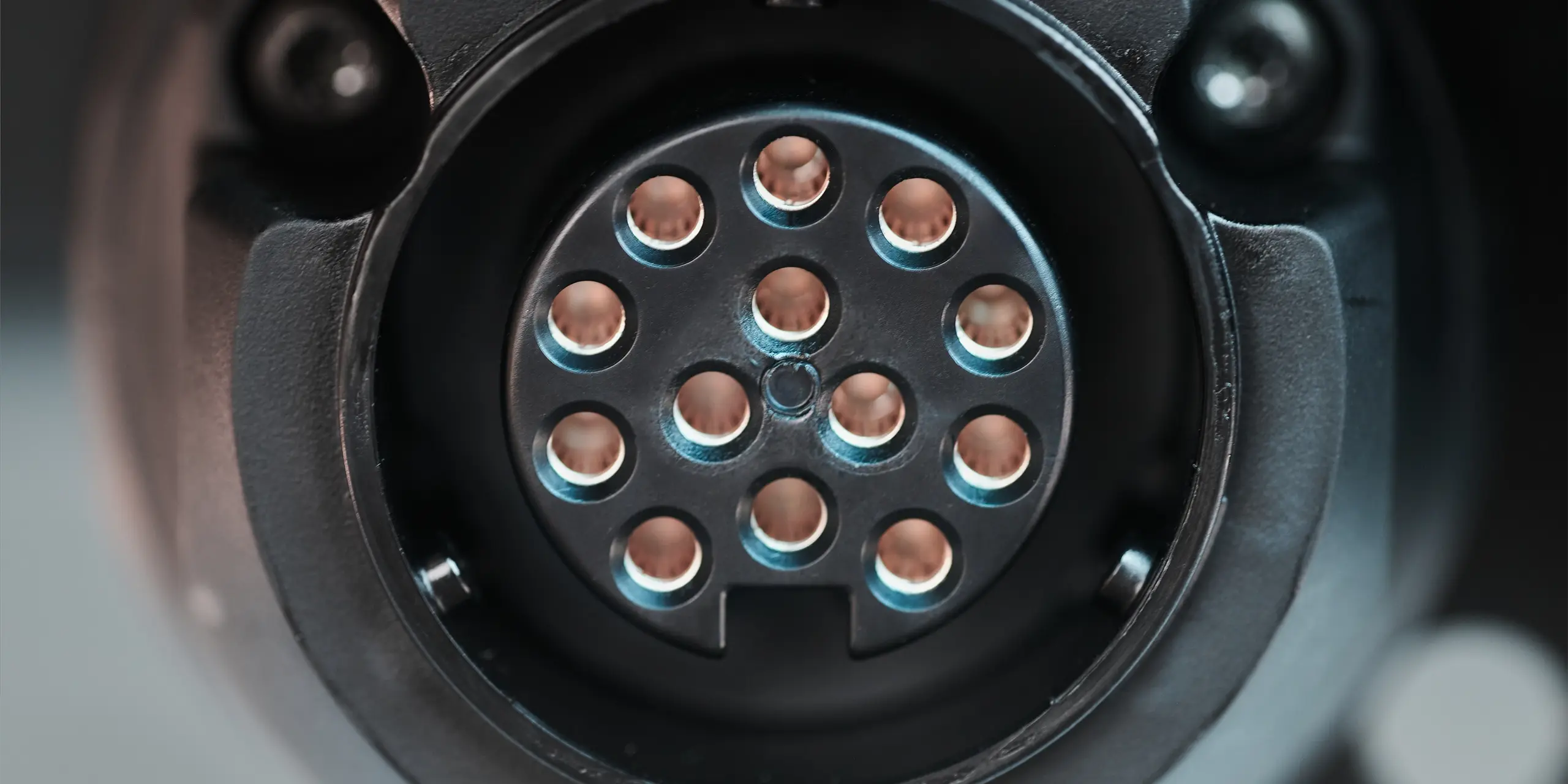 Close-up view of an electric vehicle charging connector with multiple copper pins.