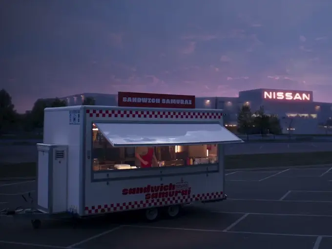 A food truck named "Sandwich Samurai" in a parking lot at dusk, with a Nissan building in the background.