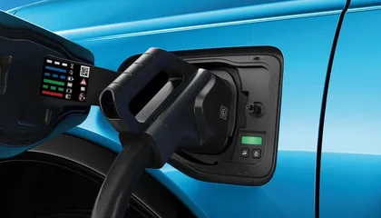 Close-up of a charging plug connected to a blue electric Nissan MICRA, displaying various indicators and buttons near the port.
