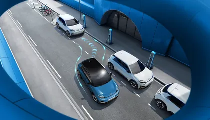 Nissan MICRA maneuvering into parallel parking spots using autonomous technology, outlined with blue guiding lines, in a modern urban setting.